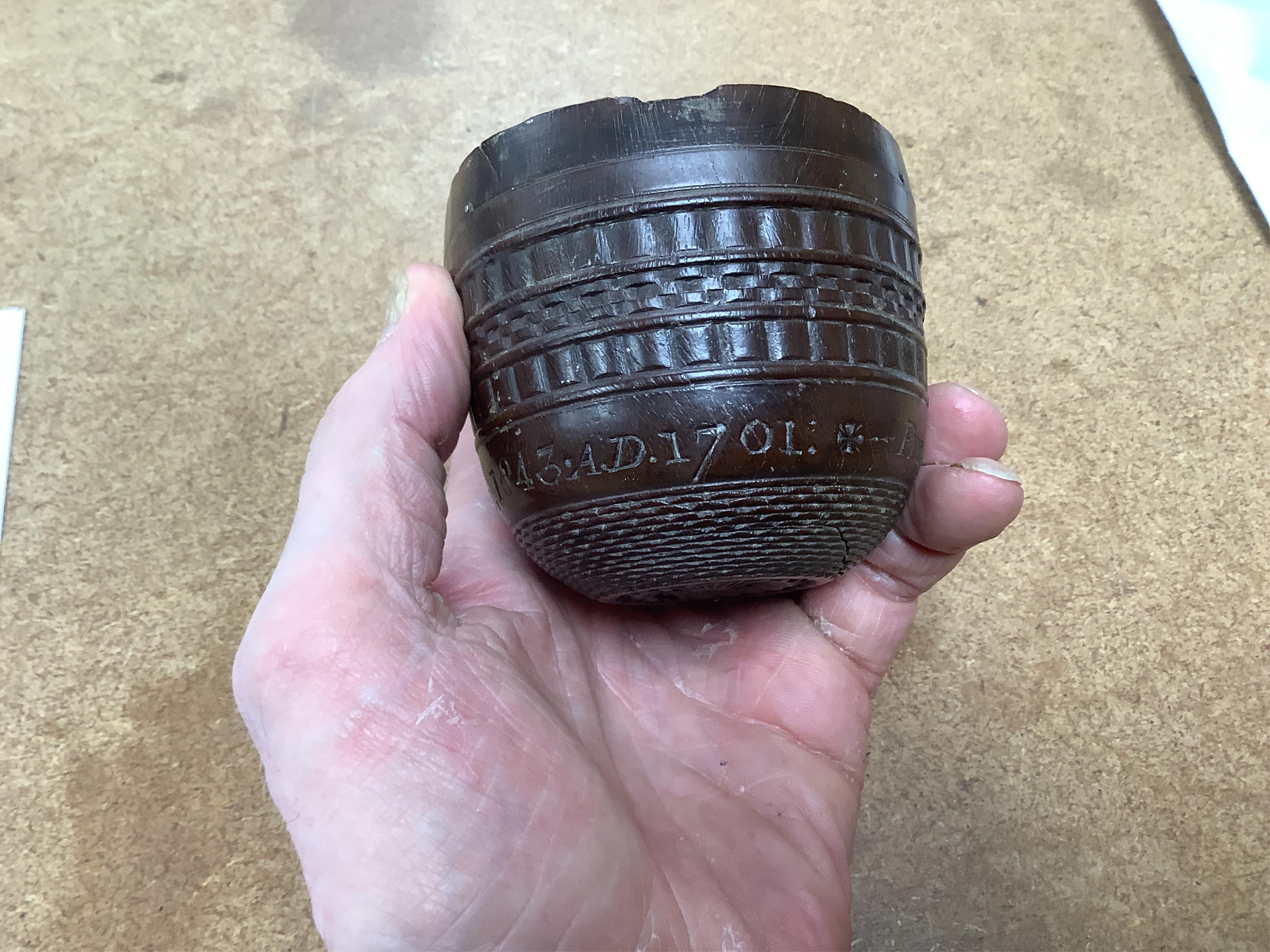 A 19th century or earlier engine-turned lignum vitae tumbler cup, engraved ‘Presented to M. S. Jones by a Friend 1843 AD 1701 +’, 6.5cm high, by repute found on the roof plate of Kenwood house London in 2012, during reno